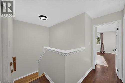 Hardwood-style flooring throughout the upper landing, a modern flush-mount ceiling light, and white wall trim - 103 Emick Drive, Ancaster, ON 