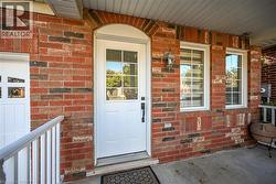 Brick exterior with an arched entryway, white door with lites, and two white-framed windows - 
