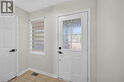 White paneled doors with matte black hardware, tiled flooring, and a decorative window - 
