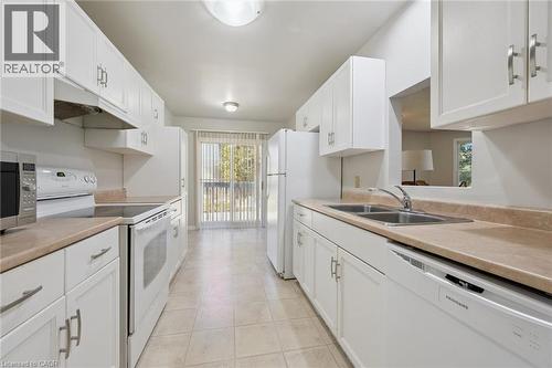 Galley kitchen featuring white cabinetry, light-toned countertops, and a double basin sink - 512 Thorndale Drive, Waterloo, ON 