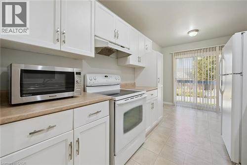 White cabinetry with silver-tone hardware, light-toned countertops, and tile flooring - 512 Thorndale Drive, Waterloo, ON 