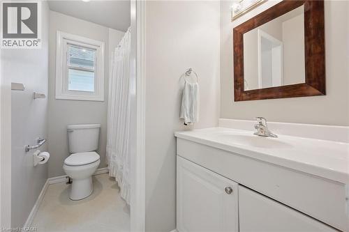 White vanity with an integrated sink and chrome faucet, set against a framed mirror with overhead lighting - 512 Thorndale Drive, Waterloo, ON 