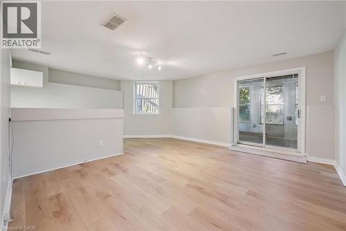 Light wood-finish flooring with a sliding glass door, overhead track lighting, and a white cabinet - 512 Thorndale Drive, Waterloo, ON 