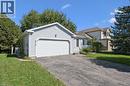 Light-colored siding exterior, attached garage with a white door, front porch with white railing, paved driveway, and mature landscaping - 512 Thorndale Drive, Waterloo, ON 