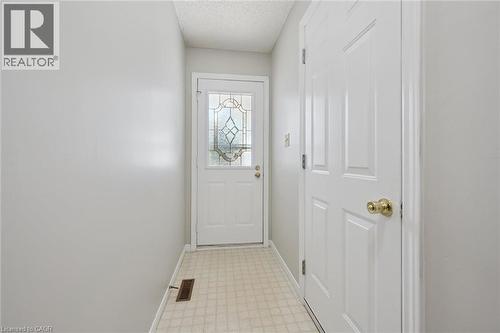 Entryway featuring a decorative glass panel door, light-toned tiled flooring, and a paneled interior door with a brass-finish knob - 512 Thorndale Drive, Waterloo, ON 