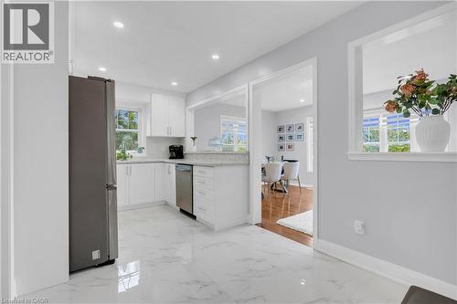 White cabinetry, light-toned countertops, stainless steel appliances, recessed lighting, and white tile flooring - 2435 Coho Way, Oakville, ON 