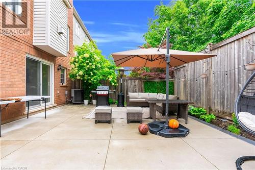 Expansive concrete patio with a privacy fence, mature perimeter landscaping, and brick exterior - 2435 Coho Way, Oakville, ON 