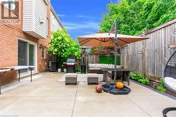 Expansive concrete patio with a privacy fence, mature perimeter landscaping, and brick exterior - 