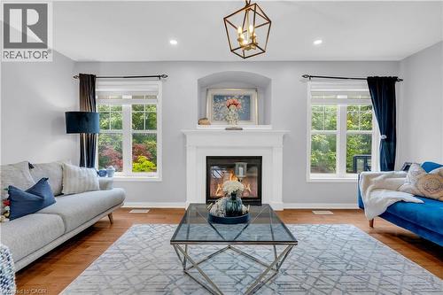 Living area featuring a classic fireplace with a white mantel, arched alcove, and wood-finish flooring - 2435 Coho Way, Oakville, ON 