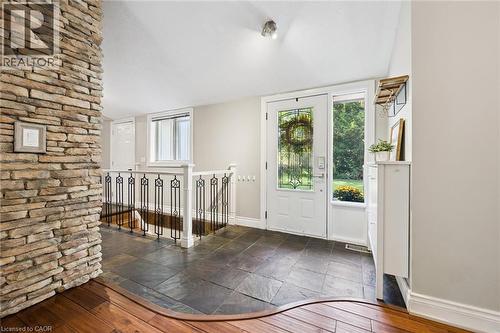 Stone accent wall, slate tile flooring, decorative glass entry door, wood-finish flooring, and white trim - 282 Concession Rd 2, Scotland, ON 