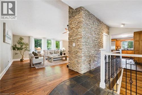 Vaulted ceiling with a ceiling fan, hardwood flooring, stone accent wall, wrought iron railing, and a bay window - 282 Concession Rd 2, Scotland, ON 