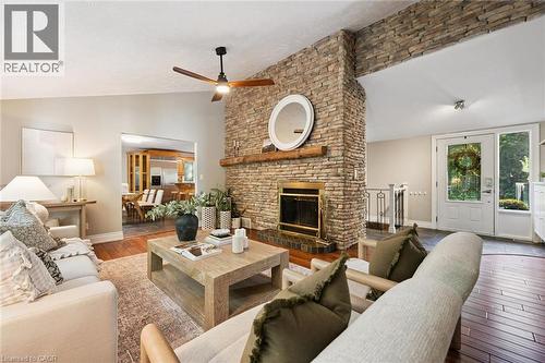 Stone-clad fireplace with a wood mantle, wood-finish flooring, a ceiling fan, and a light-filled entry with a glass-paned door - 282 Concession Rd 2, Scotland, ON 