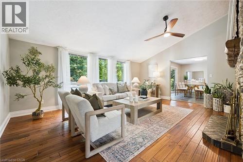 Vaulted ceiling with a ceiling fan, wood-finish flooring, stone fireplace, and a dining area - 282 Concession Rd 2, Scotland, ON 