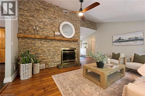 Stone-clad fireplace with a wood mantle, wood-finish flooring, and a ceiling fan - 282 Concession Rd 2, Scotland, ON 