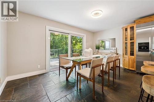 Stone tile flooring, built-in corner display cabinet, stainless steel refrigerator, and glass sliding door leading to an outdoor deck - 282 Concession Rd 2, Scotland, ON 
