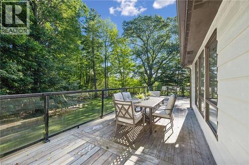 Expansive wood-finish deck with glass railing, multiple windows, and a rich green treeline - 282 Concession Rd 2, Scotland, ON 