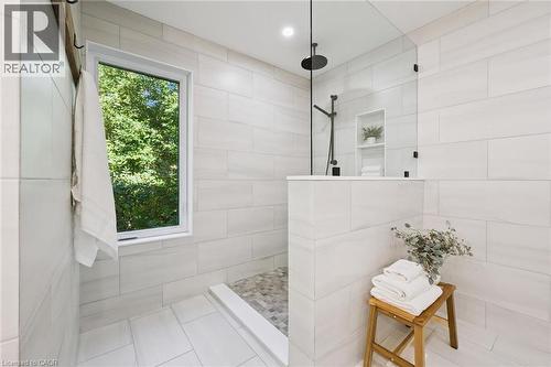 Spacious shower with large format wall tiling, mosaic floor tiling, built-in shelving, and a matte black rainfall showerhead - 282 Concession Rd 2, Scotland, ON 