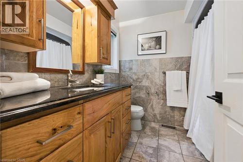 Wood vanity with a dark countertop, undermount sink, and wall-mounted mirror - 282 Concession Rd 2, Scotland, ON 
