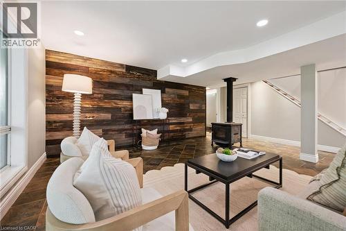 Accent wood paneling, recessed lighting, wood-burning stove, tile flooring, and a visible staircase - 282 Concession Rd 2, Scotland, ON 