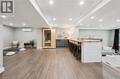 Wood-finish flooring throughout, recessed lighting, built-in bar with shiplap-style paneling, integrated sauna, and wall-mounted climate control unit - 282 Concession Rd 2, Scotland, ON 