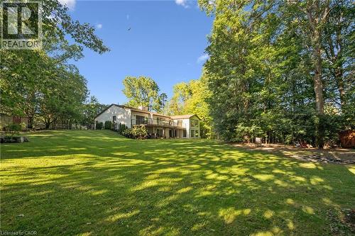Expansive manicured lawn with mature trees, a multi-level deck, and a stucco exterior - 282 Concession Rd 2, Scotland, ON 