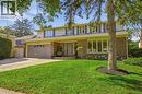 Brick exterior with light siding, front-facing garage with a paver driveway, manicured lawn with mature trees, and a covered front entry - 4159 Spruce Avenue, Burlington, ON 