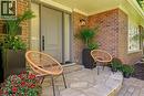Brick exterior with an entryway sconce, featuring a paneled entry door with sidelights, and a flagstone patio - 4159 Spruce Avenue, Burlington, ON 