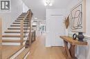 Light wood-finish flooring throughout, staircase with wood treads and metal balusters, wainscoting details, and bi-fold doors - 4159 Spruce Avenue, Burlington, ON 