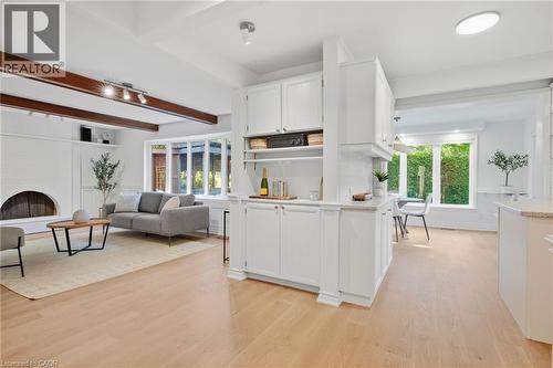 Light wood-finish flooring throughout, white cabinetry with integrated shelving, and a built-in fireplace - 4159 Spruce Avenue, Burlington, ON 