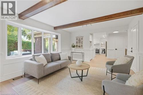 Expansive window bank, exposed wood ceiling beams, wood-finish flooring, white paneled walls, and open layout - 4159 Spruce Avenue, Burlington, ON 