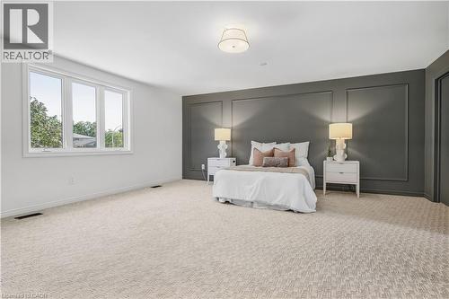 Expansive room featuring a large window, patterned carpeting, a dark accent wall with decorative molding, and an overhead flush-mount light fixture - 4159 Spruce Avenue, Burlington, ON 