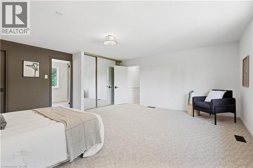 Spacious room featuring light-colored carpeting, dark accent wall, mirrored sliding closet doors, and recessed lighting - 4159 Spruce Avenue, Burlington, ON 