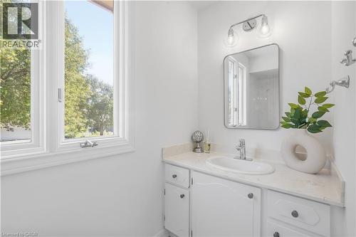 White vanity with an integrated sink, polished chrome faucet, and stone-finish countertop - 4159 Spruce Avenue, Burlington, ON 