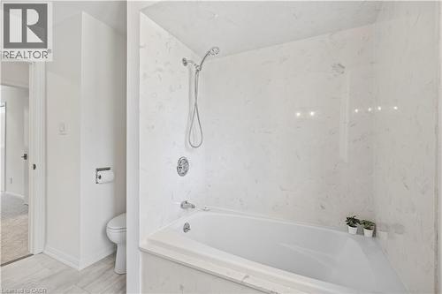Integrated tub and shower combination with white surround, chrome fixtures, and a handheld showerhead - 4159 Spruce Avenue, Burlington, ON 