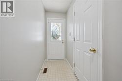 Entryway featuring a decorative glass panel door, light-toned tiled flooring, and a paneled interior door with a brass-finish knob - 