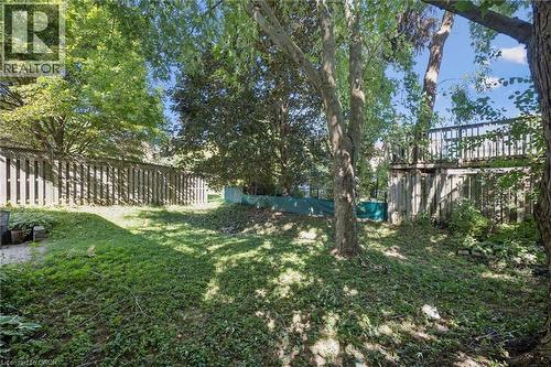 Sloped backyard with mature trees, a wooden fence, and a multi-level wooden deck structure - 512 Thorndale Drive, Waterloo, ON 