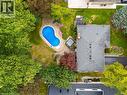 Aerial view of Kidney-shaped swimming pool with stone surround, integrated hot tub, extensive paving stone patio, and mature trees - 200 Woodview Crescent, Ancaster, ON 