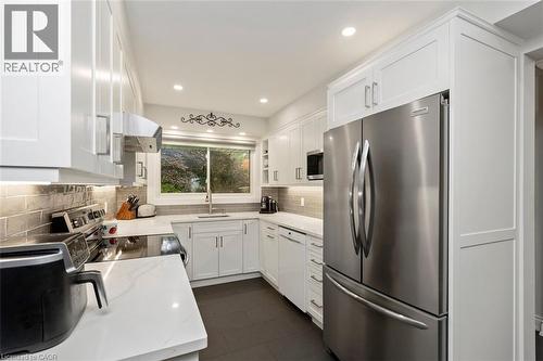 White cabinetry, stainless steel appliances, quartz counters and subway tile. View to front yard - 200 Woodview Crescent, Ancaster, ON 