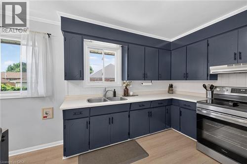 Kitchen featuring extensive navy cabinetry, a stainless steel double basin sink, white countertops, and a white subway tile backsplash - 13 Allanburg Road S, St. Catharines, ON 