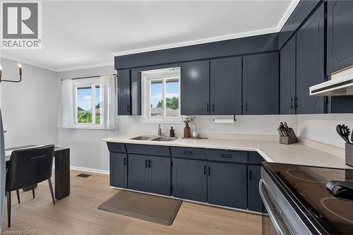 Modern kitchen featuring custom dark cabinetry with ample storage, white subway tile backsplash, and stainless steel appliances - 13 Allanburg Road S, St. Catharines, ON 