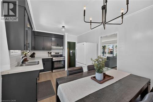 Contemporary kitchen and dining area featuring sleek charcoal cabinetry with white subway tile backsplash, stainless steel appliances, and a spacious island with wood-finish countertop - 13 Allanburg Road S, St. Catharines, ON 