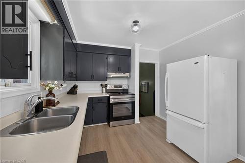 Kitchen featuring black cabinetry, stainless steel range, double basin sink, light-toned countertops, and wood-finish flooring - 13 Allanburg Road S, St. Catharines, ON 