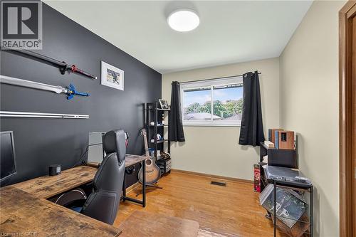 Versatile bonus room featuring hardwood flooring, a dark accent wall with mounted shelving and rod systems, recessed ceiling lighting, and a large window with black-framed glass - 13 Allanburg Road S, St. Catharines, ON 