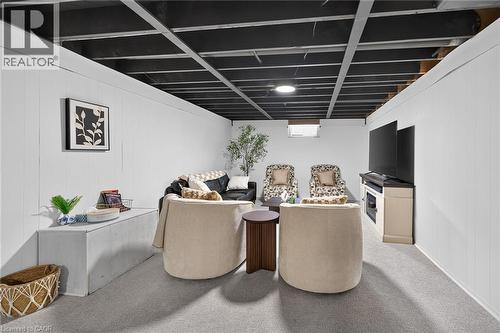 Finished basement space featuring a black exposed ceiling, white paneled walls, and soft gray carpeting - 13 Allanburg Road S, St. Catharines, ON 