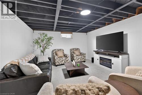 Finished basement recreation room featuring a built-in entertainment center with fireplace insert, recessed lighting, and exposed beam ceiling - 13 Allanburg Road S, St. Catharines, ON 