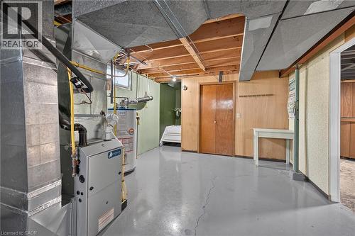 Finished basement featuring polished concrete flooring, exposed wood-beam ceiling details, and multiple storage areas with wood-finish cabinetry - 13 Allanburg Road S, St. Catharines, ON 