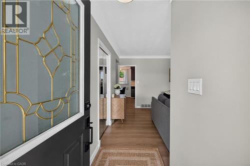 Entryway featuring a dark paneled door with decorative leaded glass, wood-finish flooring, light gray wall paint, and white trim - 13 Allanburg Road S, St. Catharines, ON 