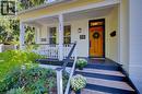Covered front porch with white railing, wood-finish steps, and a natural wood entry door - 59 Allen Street W, Waterloo, ON 
