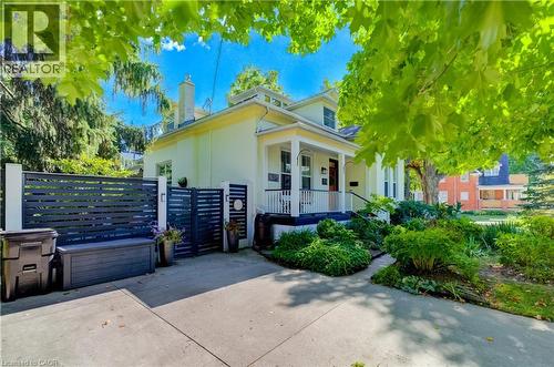Paved driveway with a modern slat fence, mature trees, and landscaping - 59 Allen Street W, Waterloo, ON 