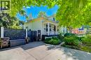 Paved driveway with a modern slat fence, mature trees, and landscaping - 59 Allen Street W, Waterloo, ON 